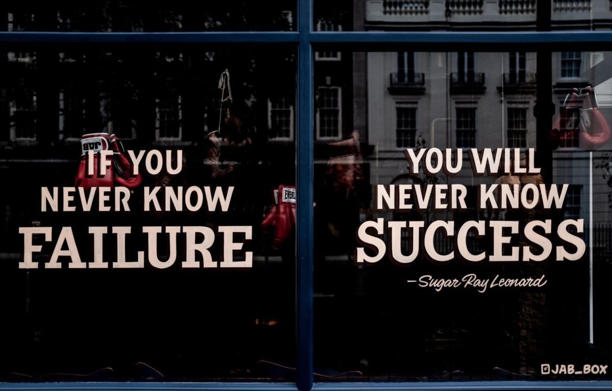 The image shows a window with the quote: If you never know failure, you will never know success – Sugar Ray Leonard, with boxing gloves reflected on the glass, reminding us how to use failure to succeed.
